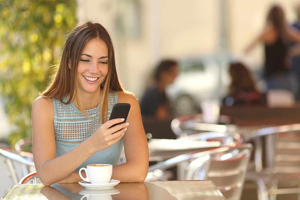 Smiling woman checking her phone while having coffee at a coffee shop