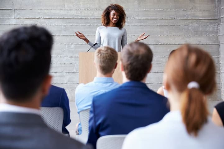 Smiling woman at podium lecturing to a group