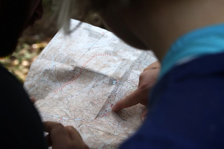 person in blue shirt pointing to destination on a map