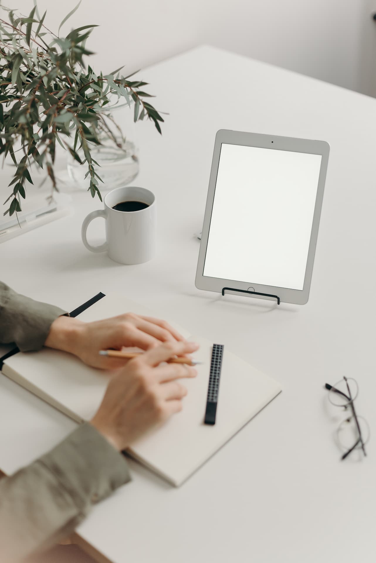 Business person writing down goals on white paper at white table.