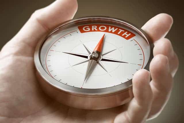 Hand holding a compass pointing north to Growth.