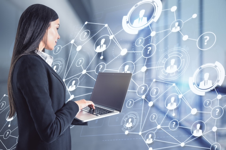 Businesswoman using laptop in office with abstract social network hologram.