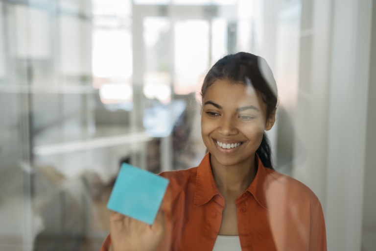 Woman writing on a post-it note.