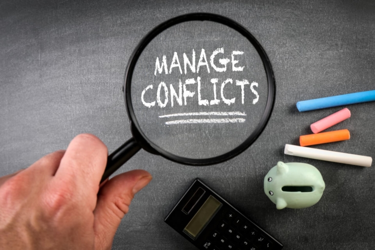 Magnifying glass showcasing the words 'Manage Conflicts'.