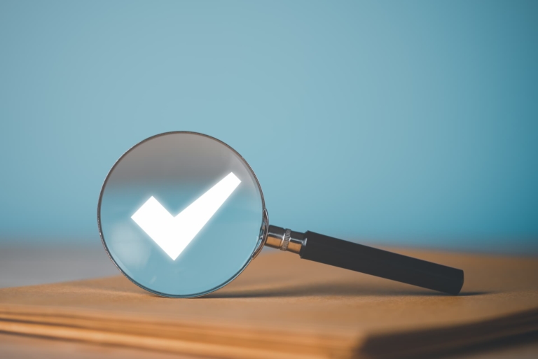 Magnifying glass showcasing a checkmark in the lens.