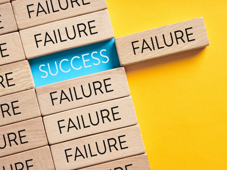 Wooden blocks with the word “failure” written in them, but one is moved showing that the word “success” lies beneath each failure.