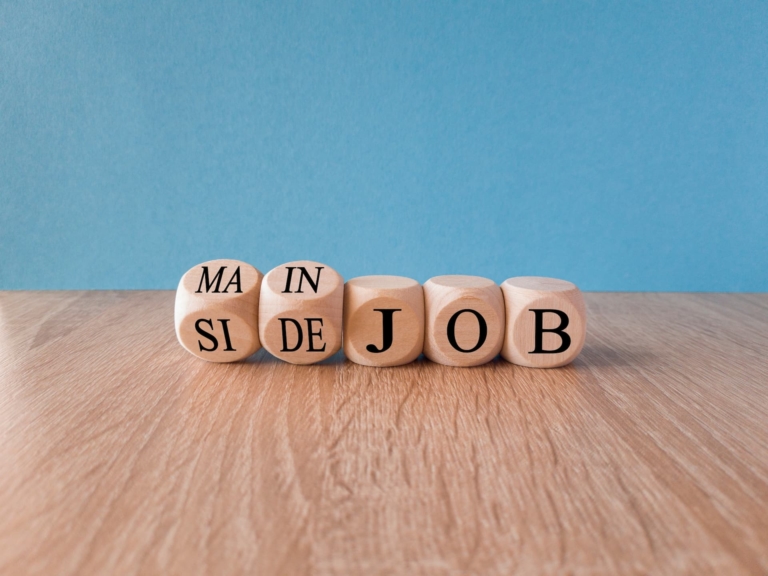 Turned wooden cubes on beautiful wooden table spelling Main Job and Side Job.