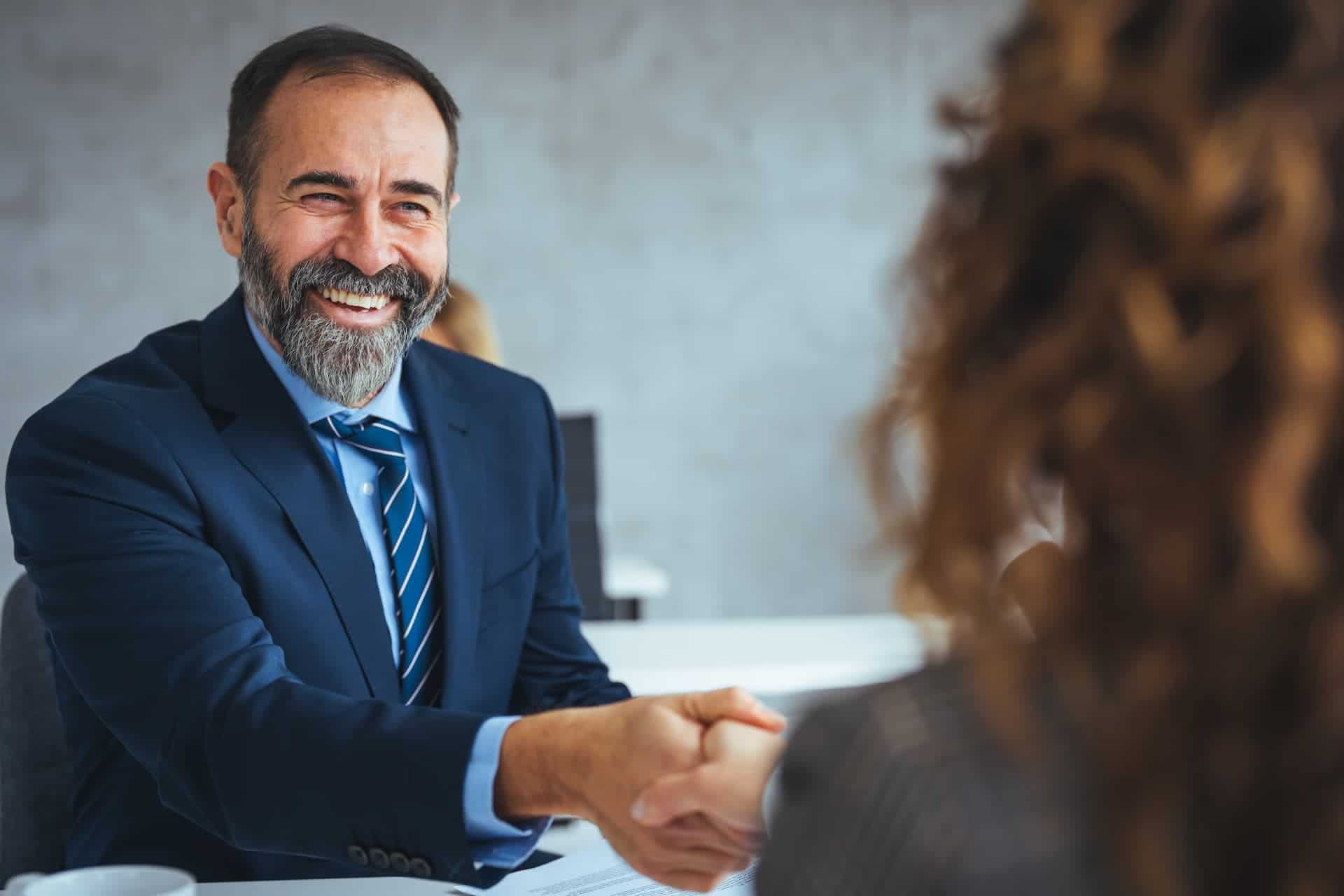 A man smiling and shaking the hand of the interviewer.