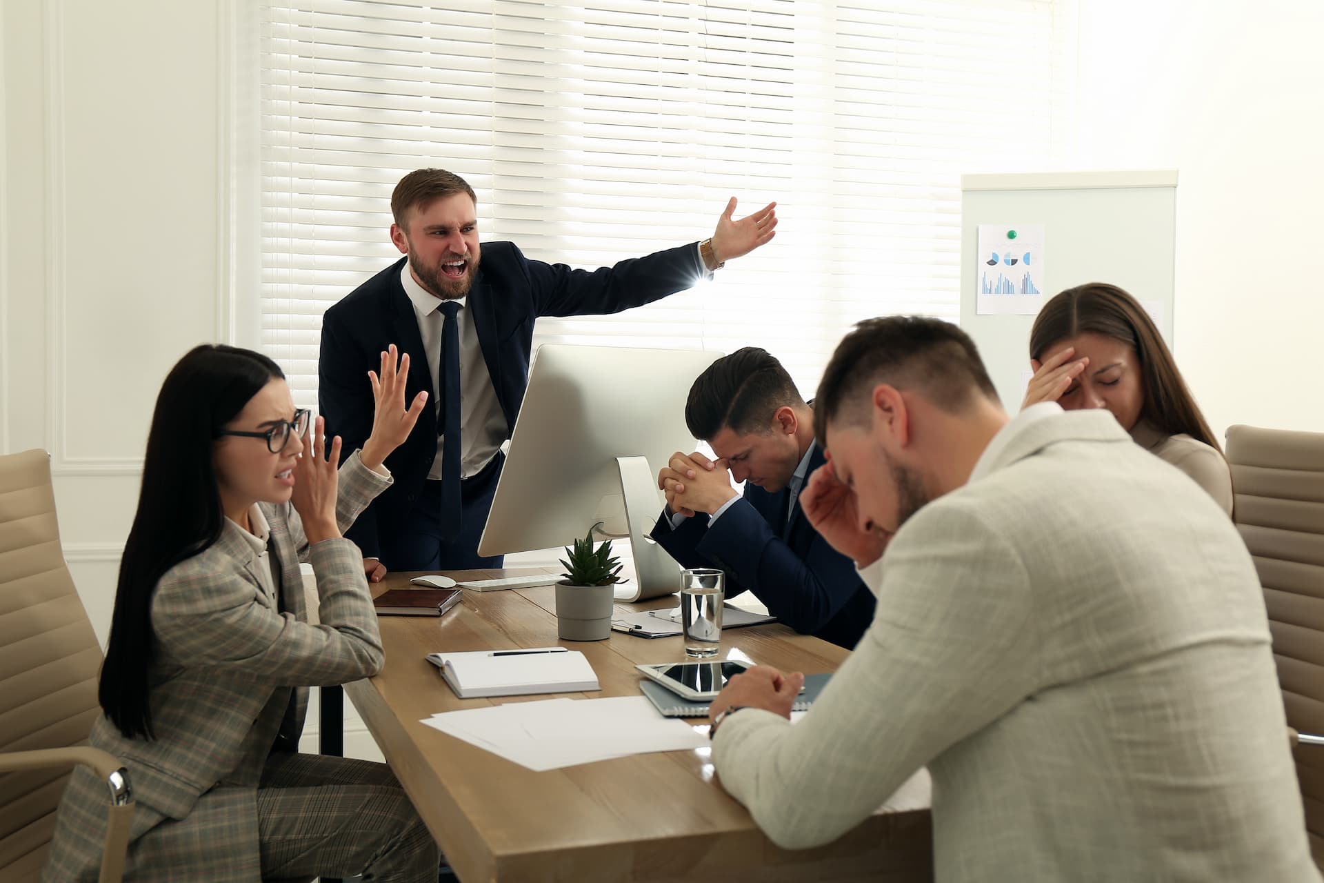 Boss screaming at employees at meeting in office showing a toxic work environment.
