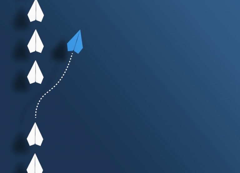 White paper planes in a row on blue background and one blue paper plane going in different direction.