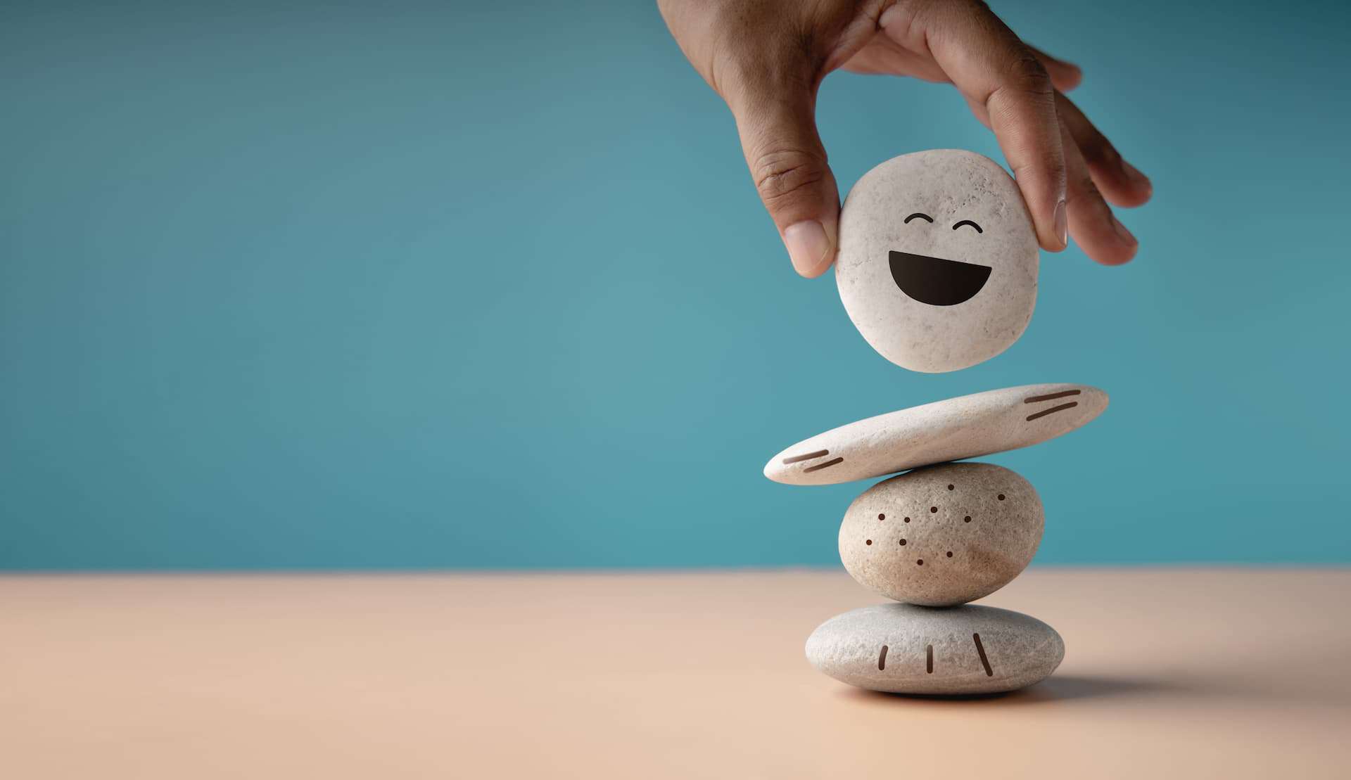 A stack of three balanced rocks with a fourth one with a drawn smiling face at the top. 