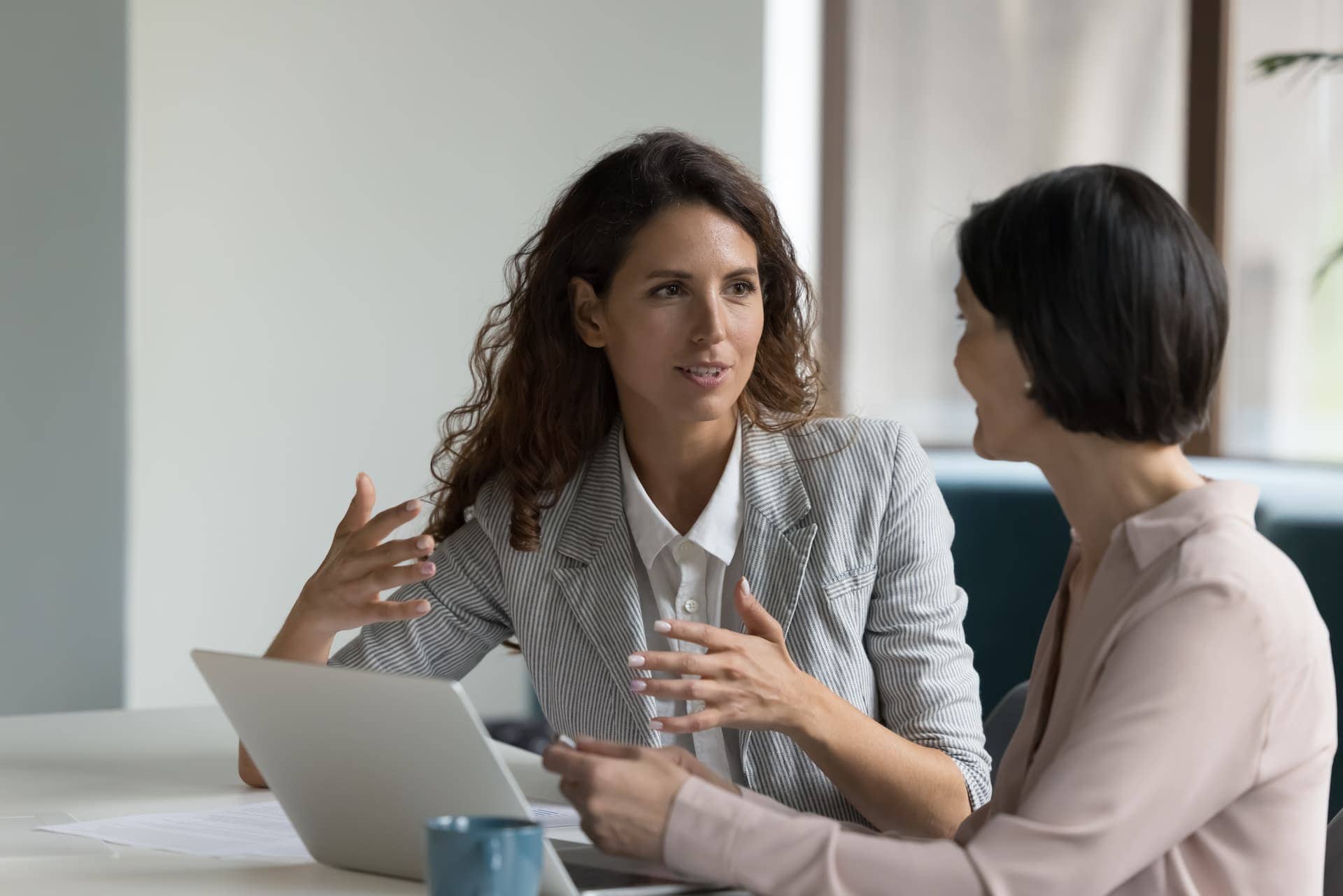 A professional woman engaged in a coaching session with her coach in an office setting, discussing growth and development opportunities.