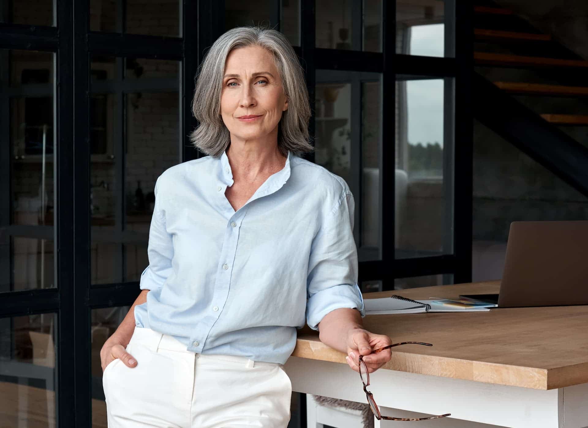 Embodying respected authority, a middle-aged woman exudes confidence and grace in a formal blue shirt paired with white pants, capturing the essence of executive presence.