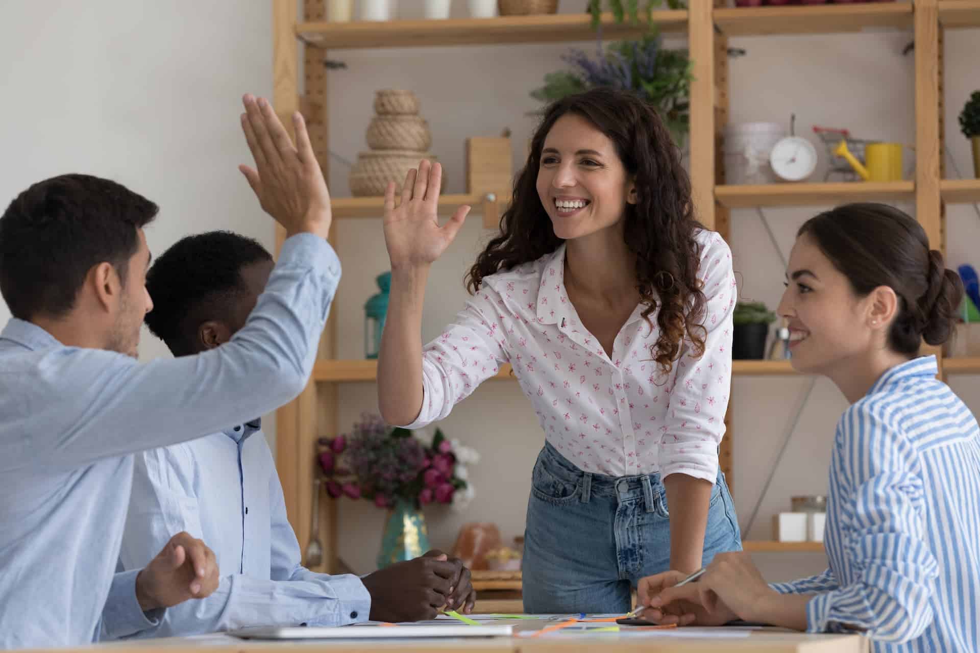 Team from work enthusiastically high-fiving, reflecting motivation and teamwork spirit.