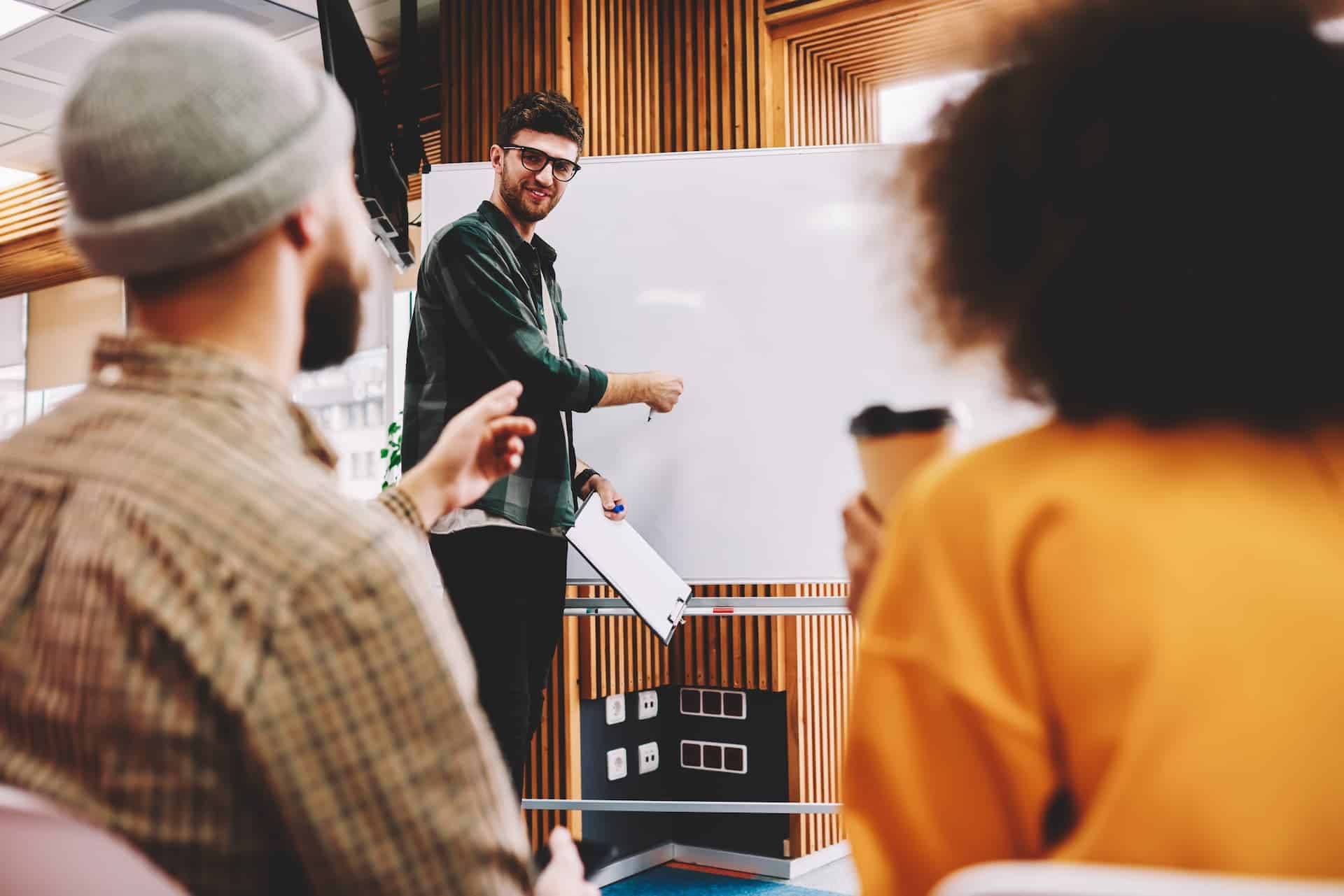 A leader facilitating a brainstorming session, encouraging team members to share ideas and collaborate creatively, with a whiteboard or flip chart visible in the background, illustrating the supportive and empowering leadership style conducive to fostering creativity.