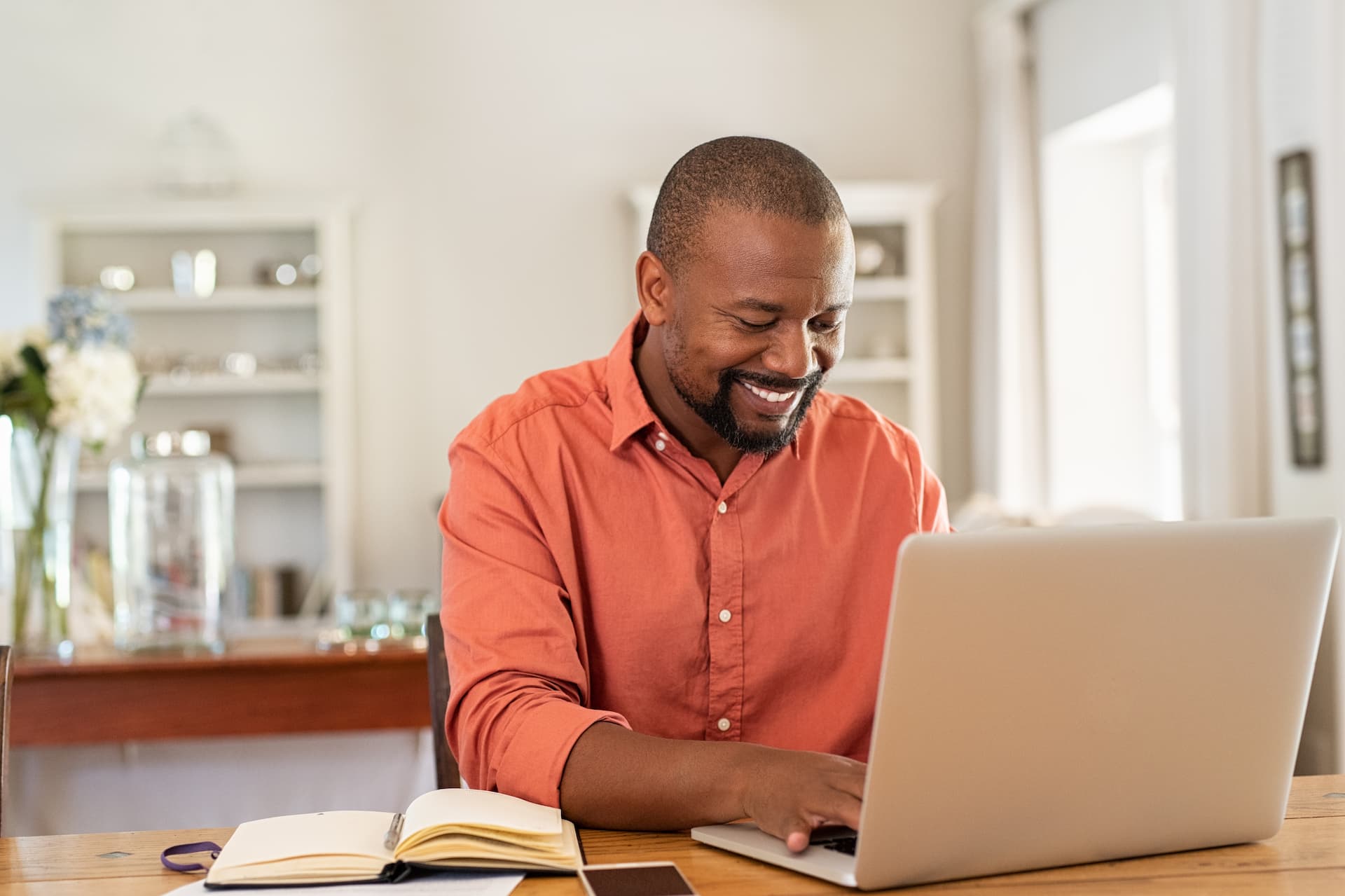 Man at home taking a career-related course on his laptop and taking notes.