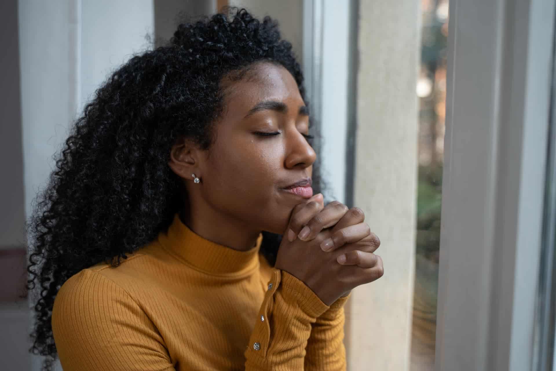 Woman praying to engage in self-care. 