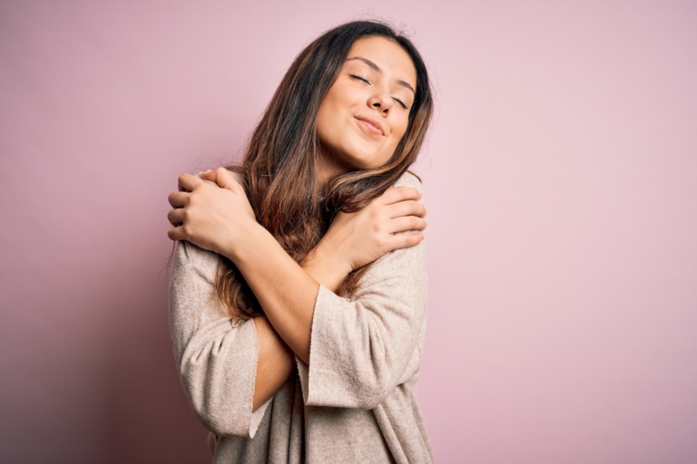 Woman hugging herself denoting the importance of self-care.