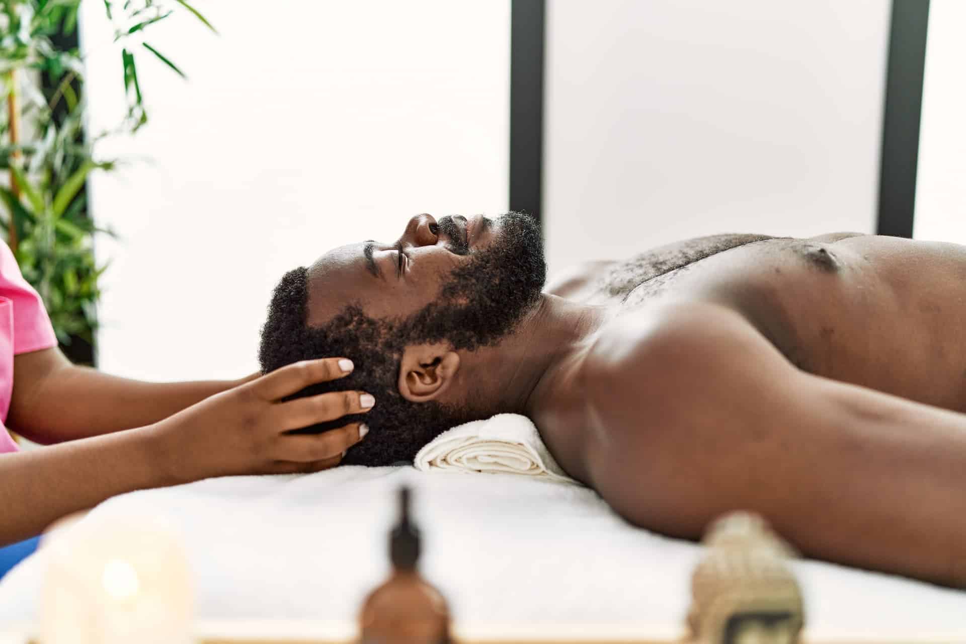 Man in a spa receiving a head massage as a form of self-care. 