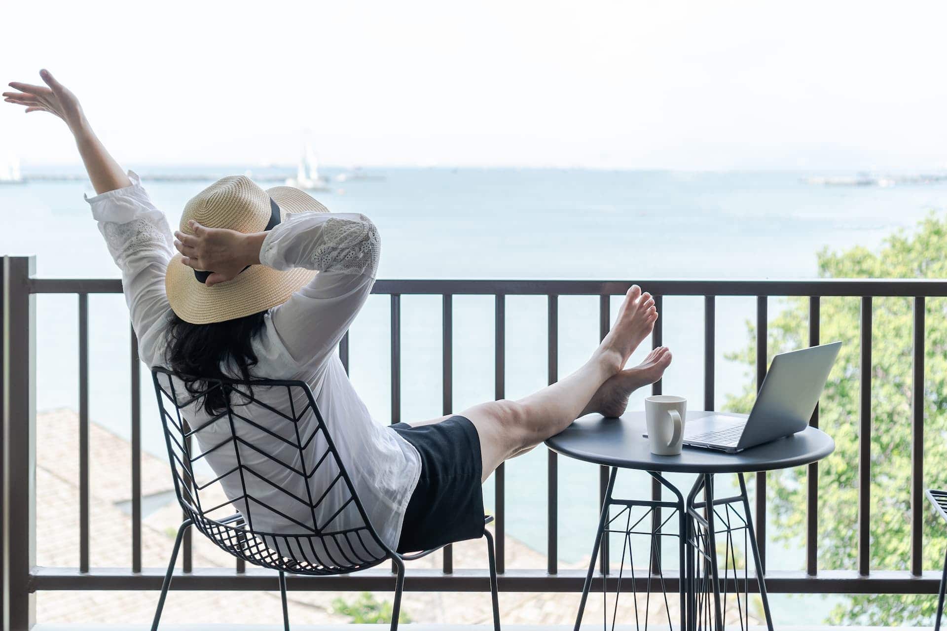 Woman in a hotel balcony, enjoying her vacation time at the beach, prioritizing self-care. 