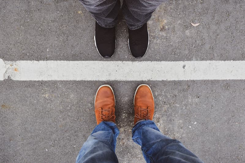 Two men standing opposite each other with a line on the asphalt between their feet, representing the concept of work boundaries.