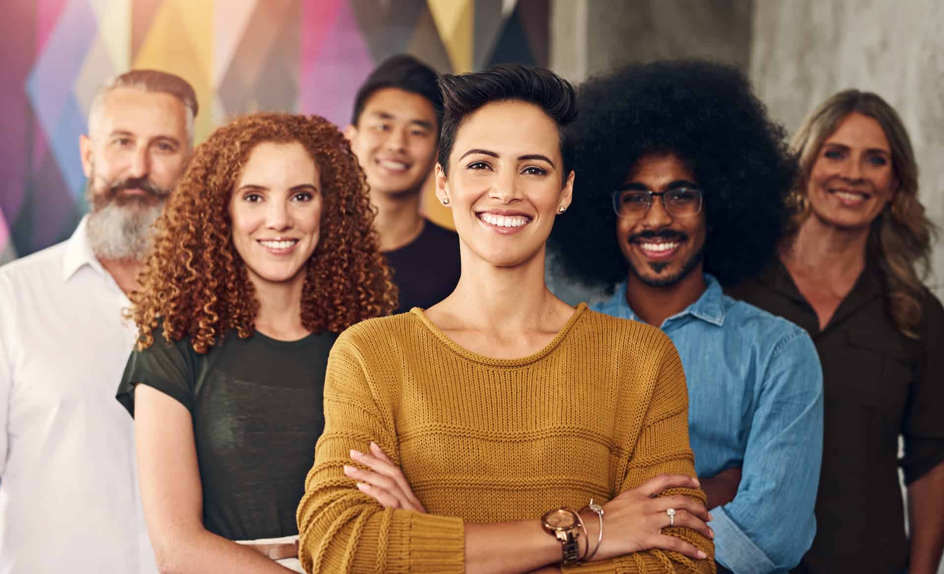 A team of workers standing in their office with arms crossed, exuding confidence and conviction.