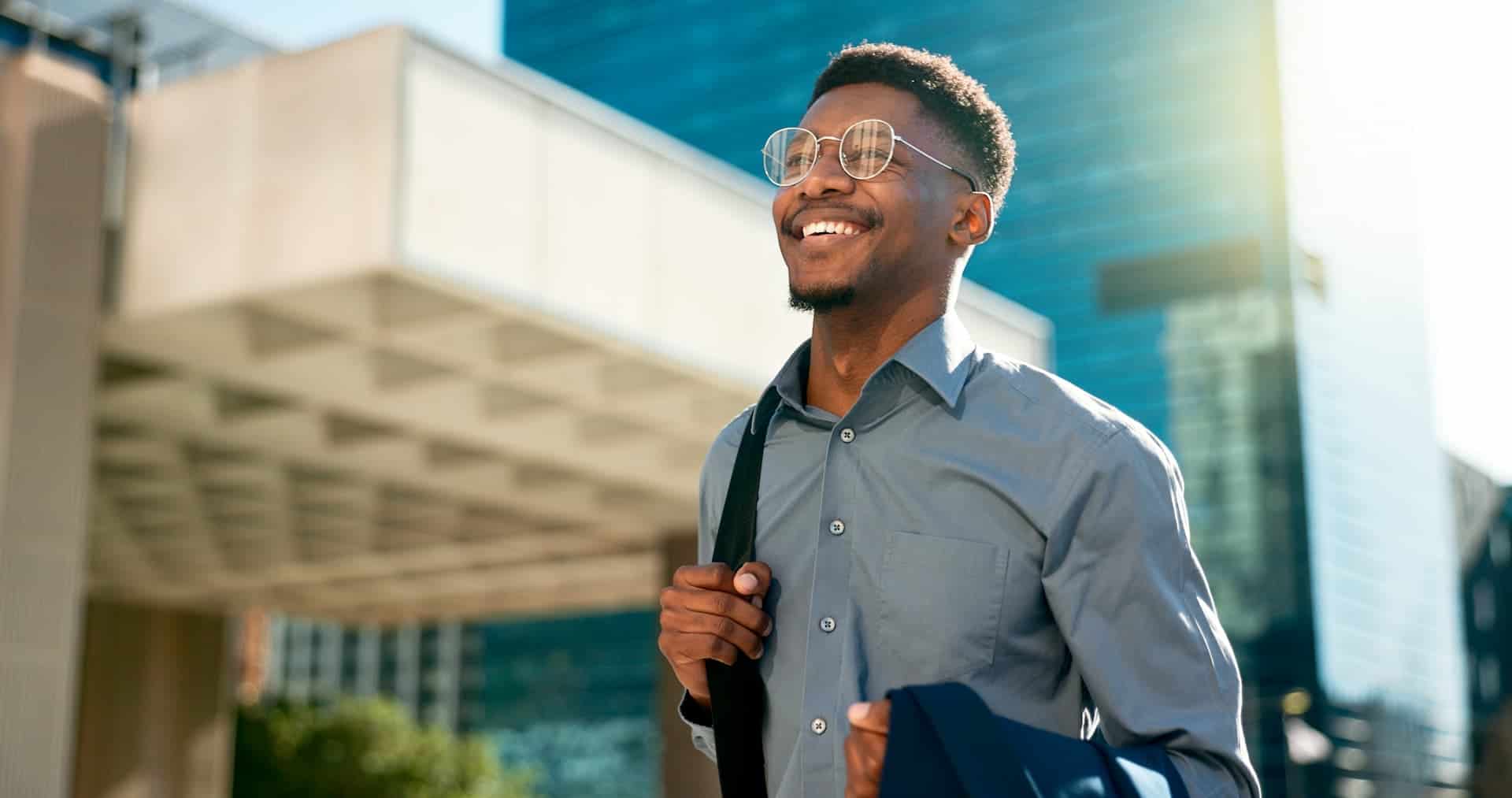 Man walking through a city with a joyful expression, holding a briefcase, showing excitement and adaptability to start a new job.