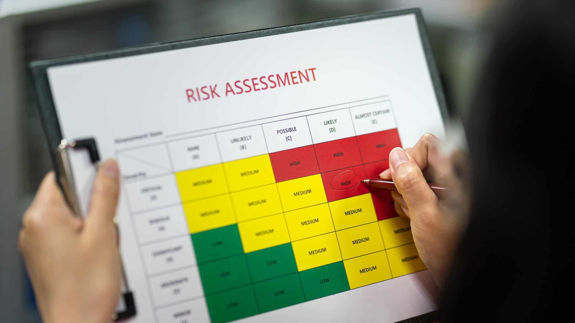 Close-up of a woman’s hand filling in a risk assessment chart.