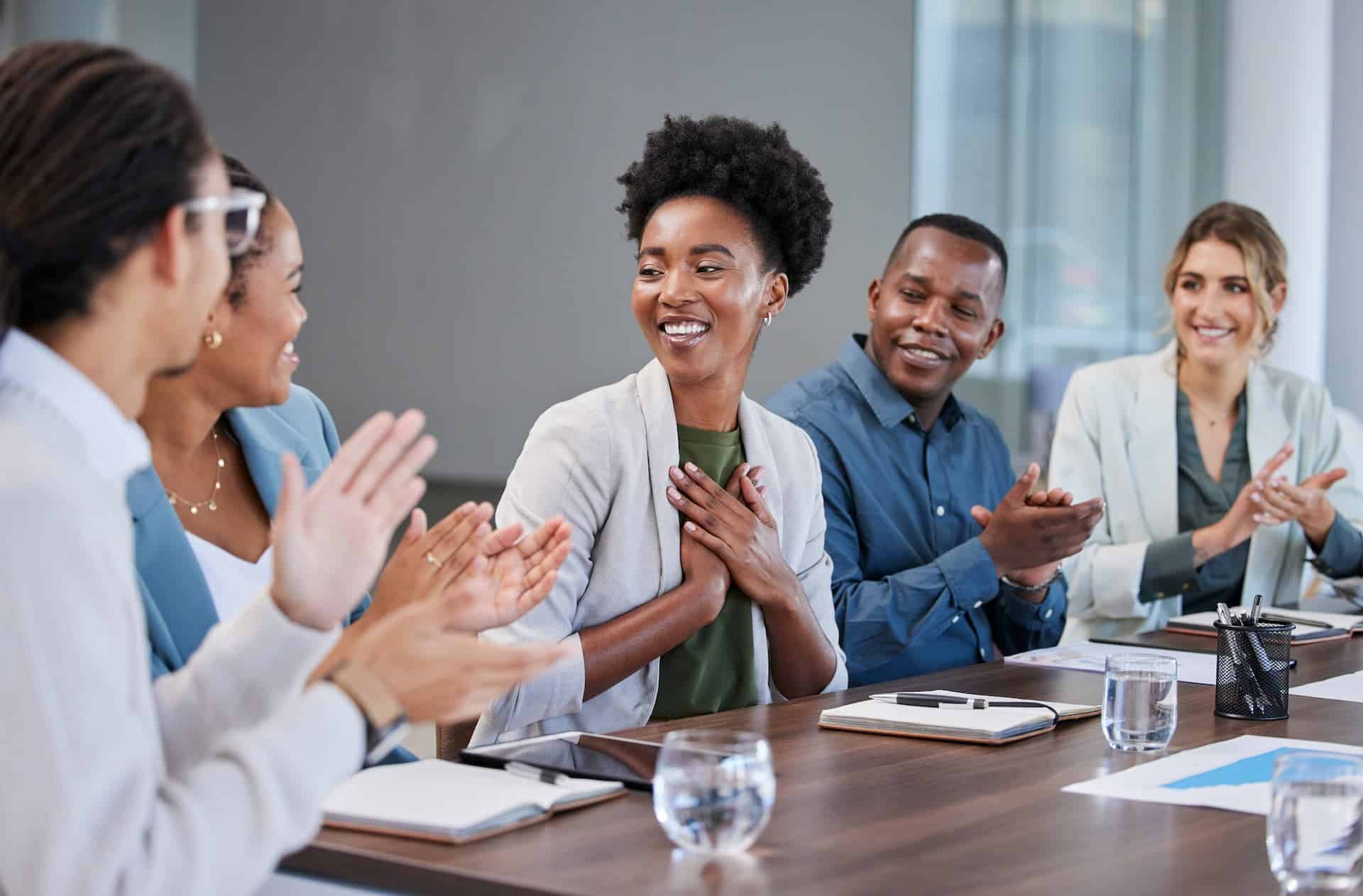 A group of colleagues applauding a woman in an office after her promotion, celebrating her self-advocacy.
