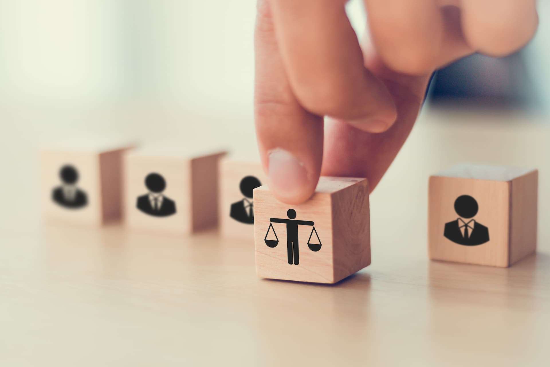 A man's hand pushing a die that displays a balance scale icon, representing a choice towards ethical action.
