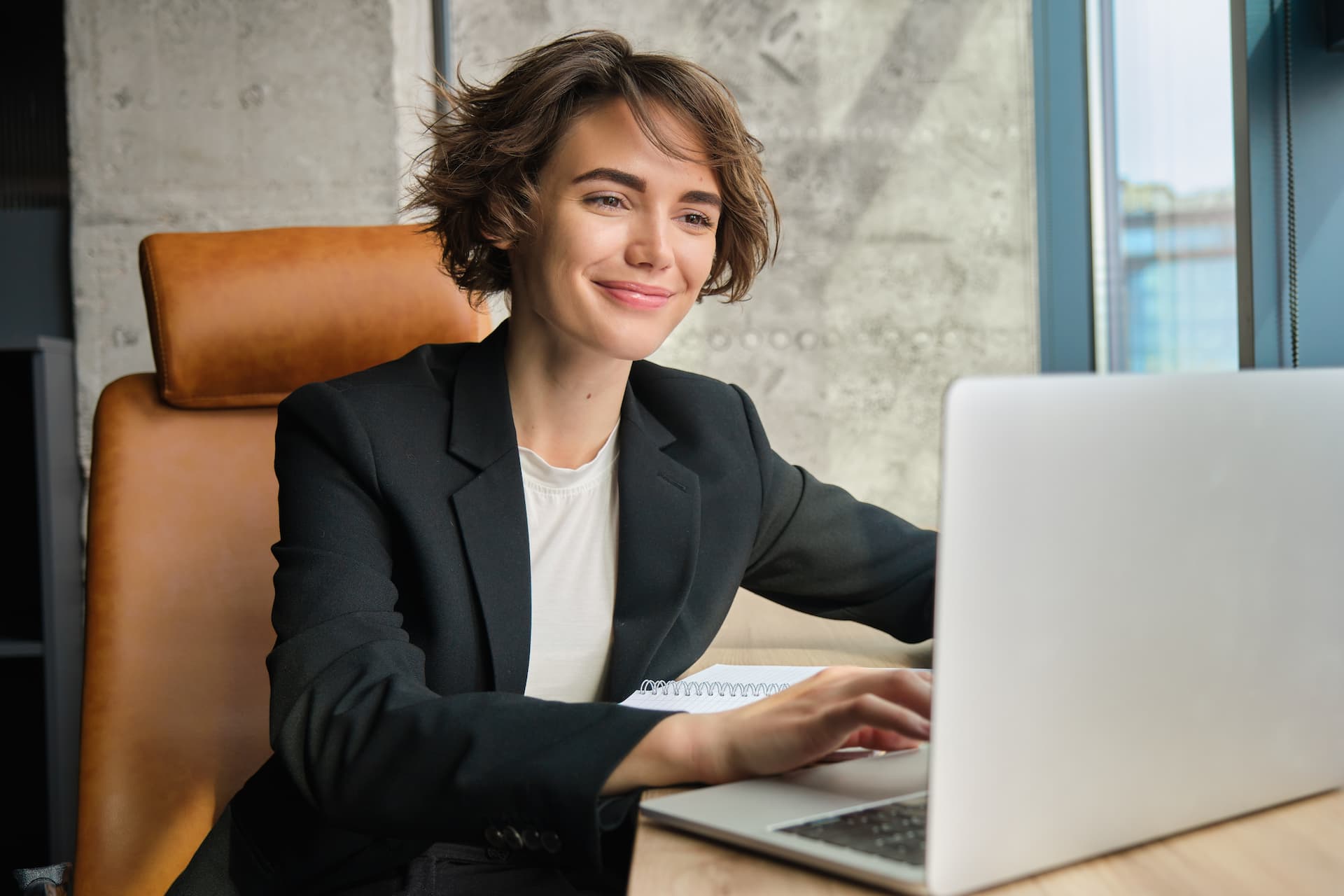 A woman sitting at a desk, with her laptop open in front of her, preparing a performance review session.