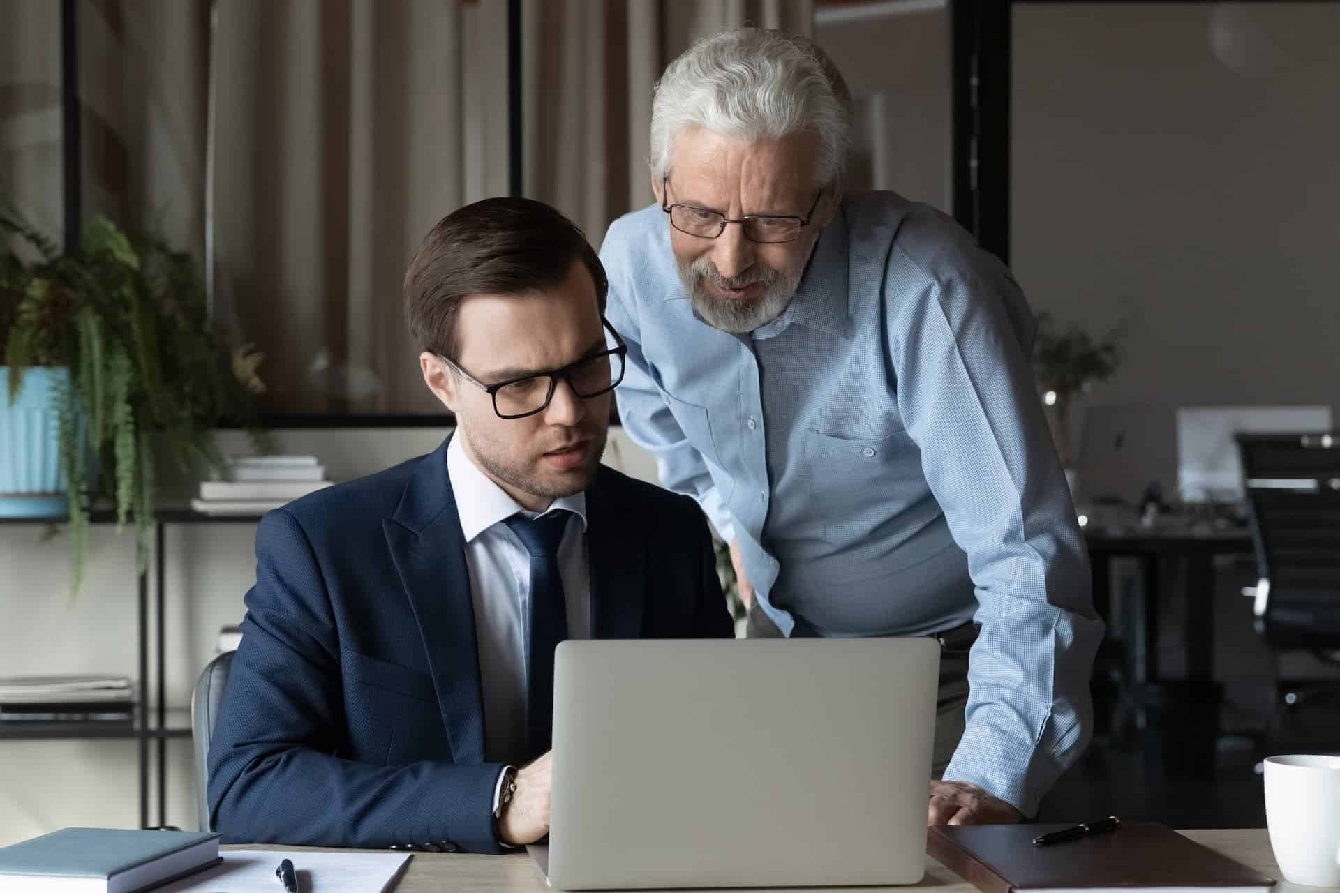 An experienced CEO guiding and mentoring a successor, symbolizing the transfer of knowledge and leadership as part of a lasting career legacy.