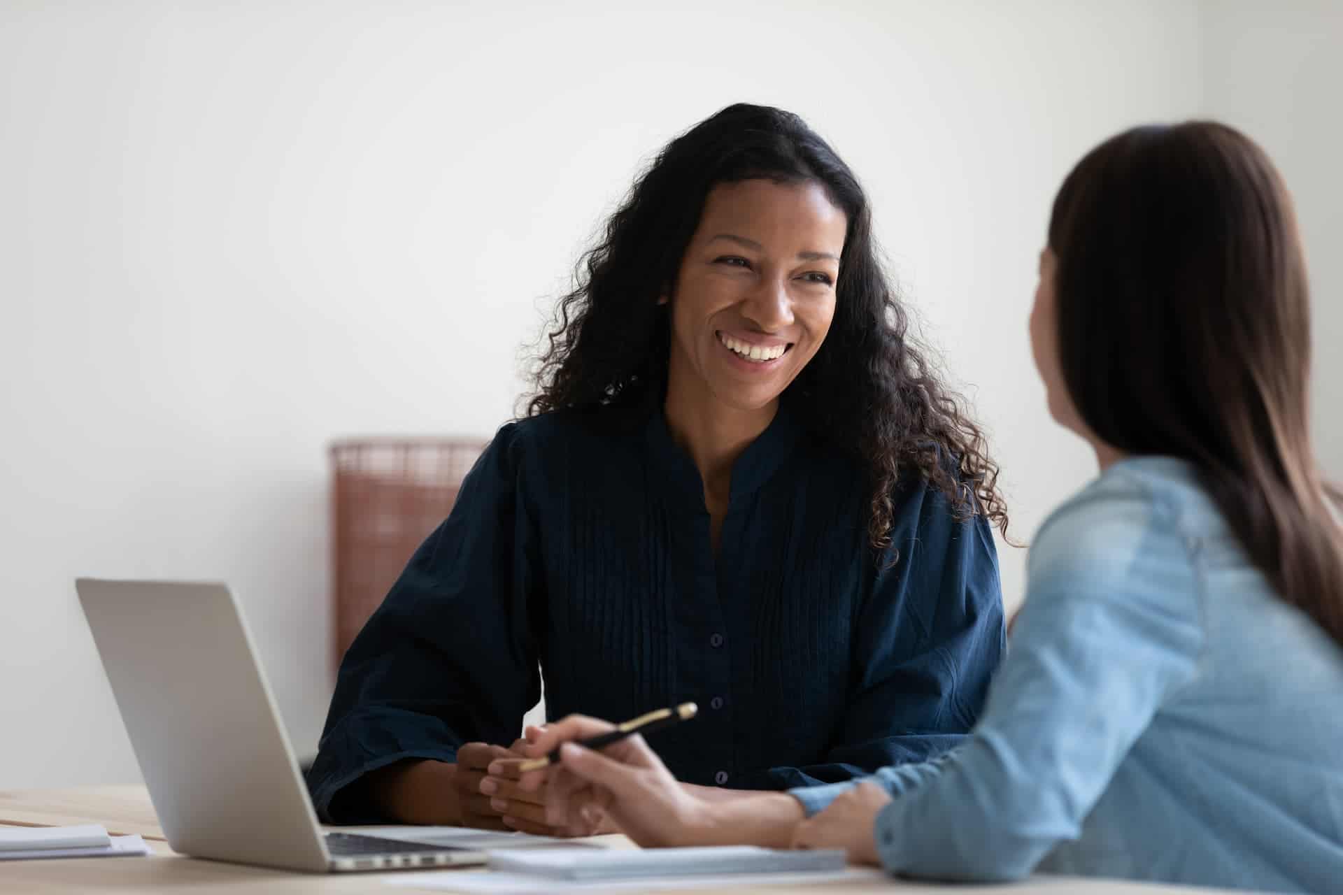 A manager giving feedback with a warm smile, demonstrating supportive and open body language to create a positive and approachable atmosphere.