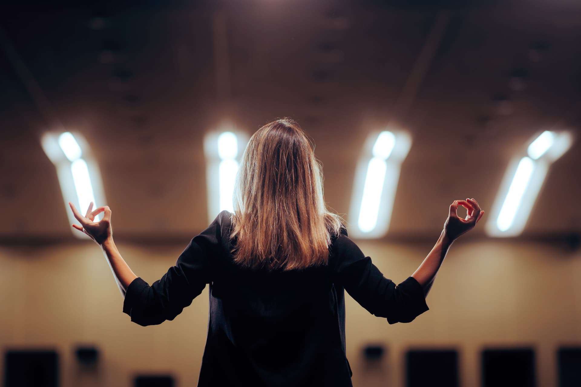 A woman speaking publicly with expressive hand gestures, using body language to emphasize her message and engage her audience.