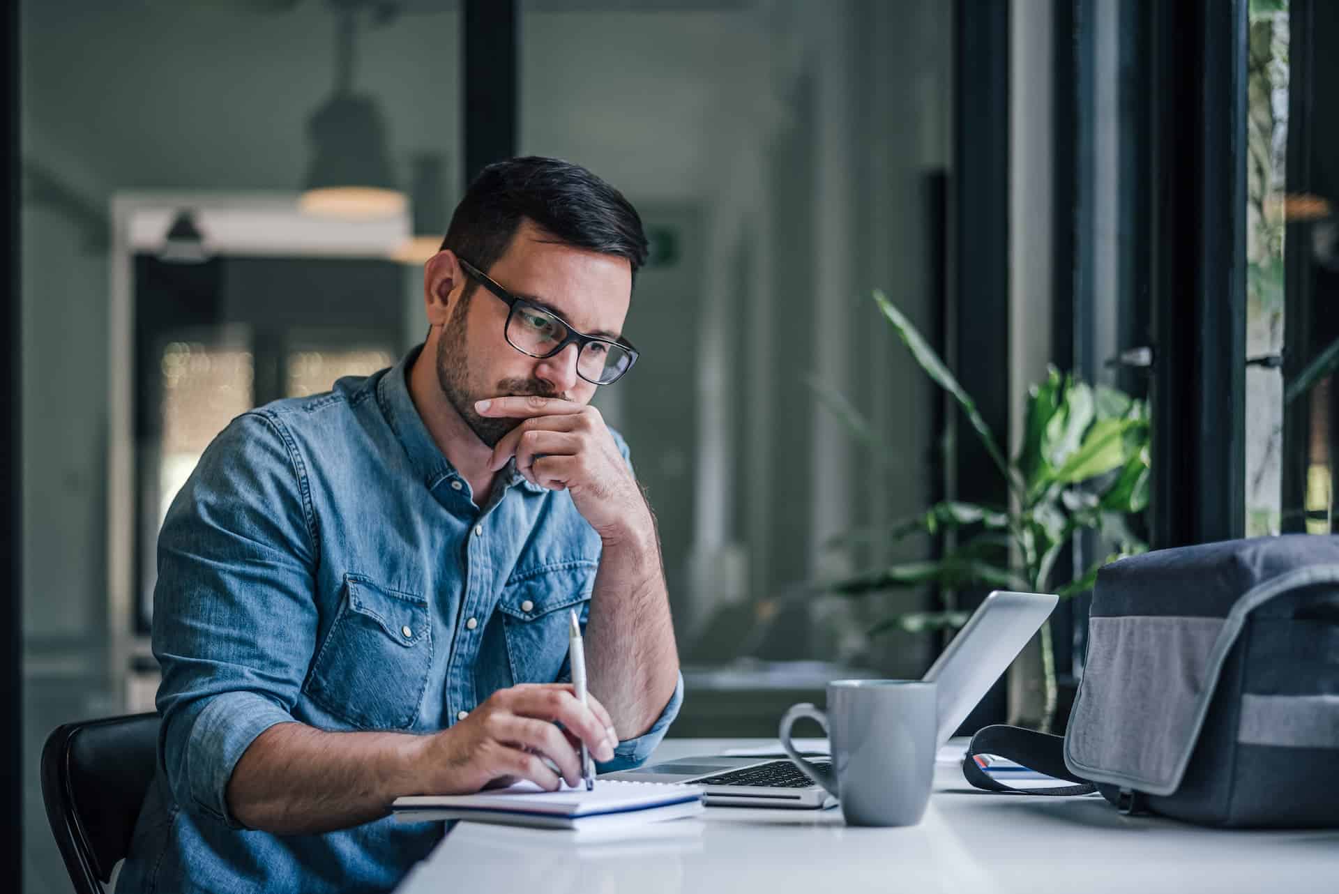 A man in an office diligently working on his laptop, representing consistent effort.