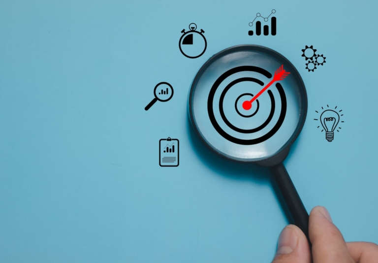 A hand holding a magnifying glass over a target, symbolizing the deep work and focus required to achieve professional goals.