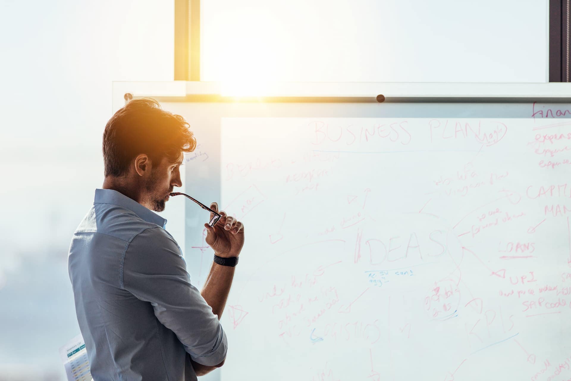 A man intensely focused on his work as he examines a whiteboard, embodying the concentration required for deep work.