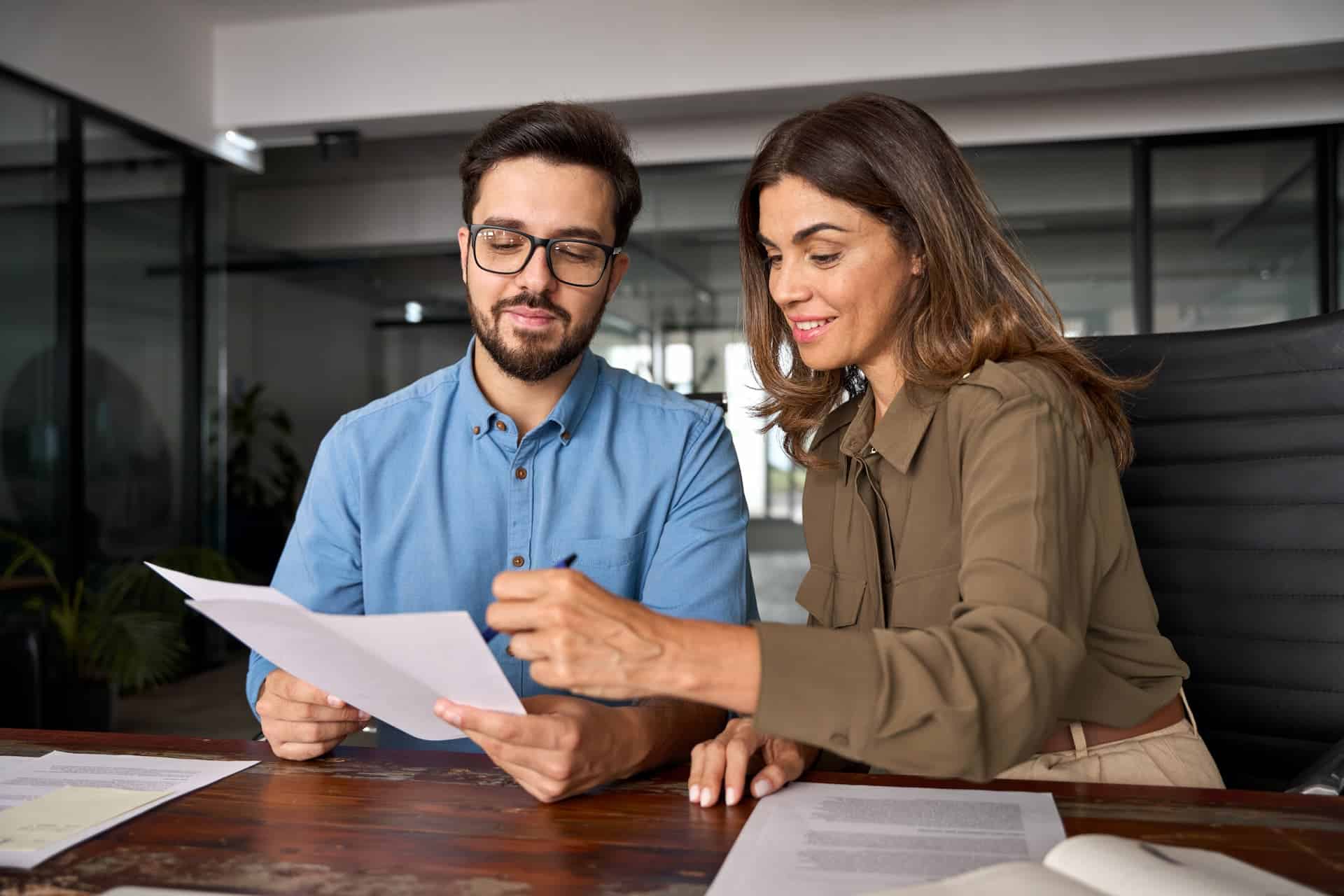 A man and woman reviewing and synthesizing findings from a report file.
