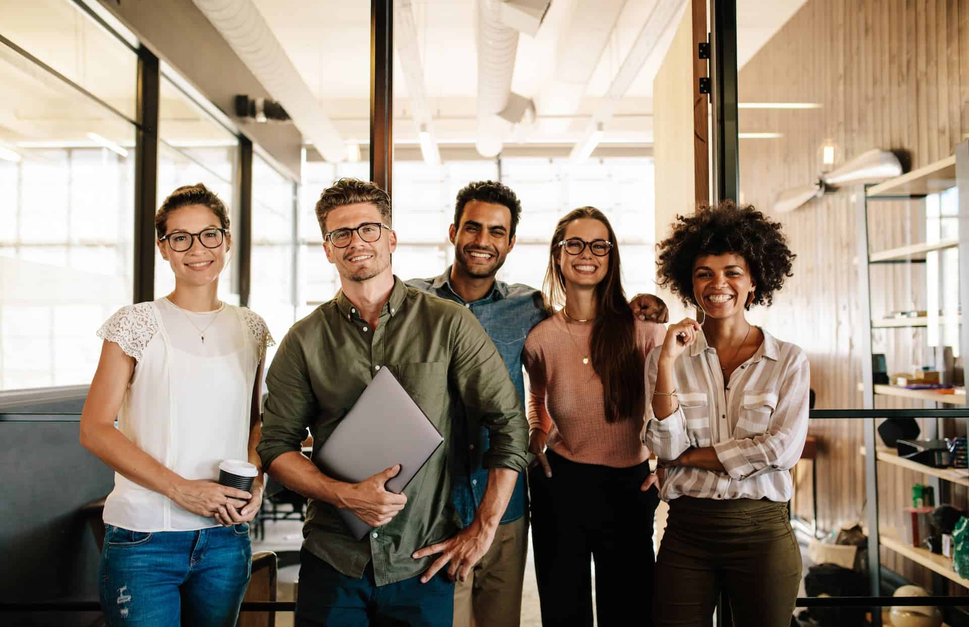 Happy, diverse, creative business team at a startup standing together and smiling toward the camera.