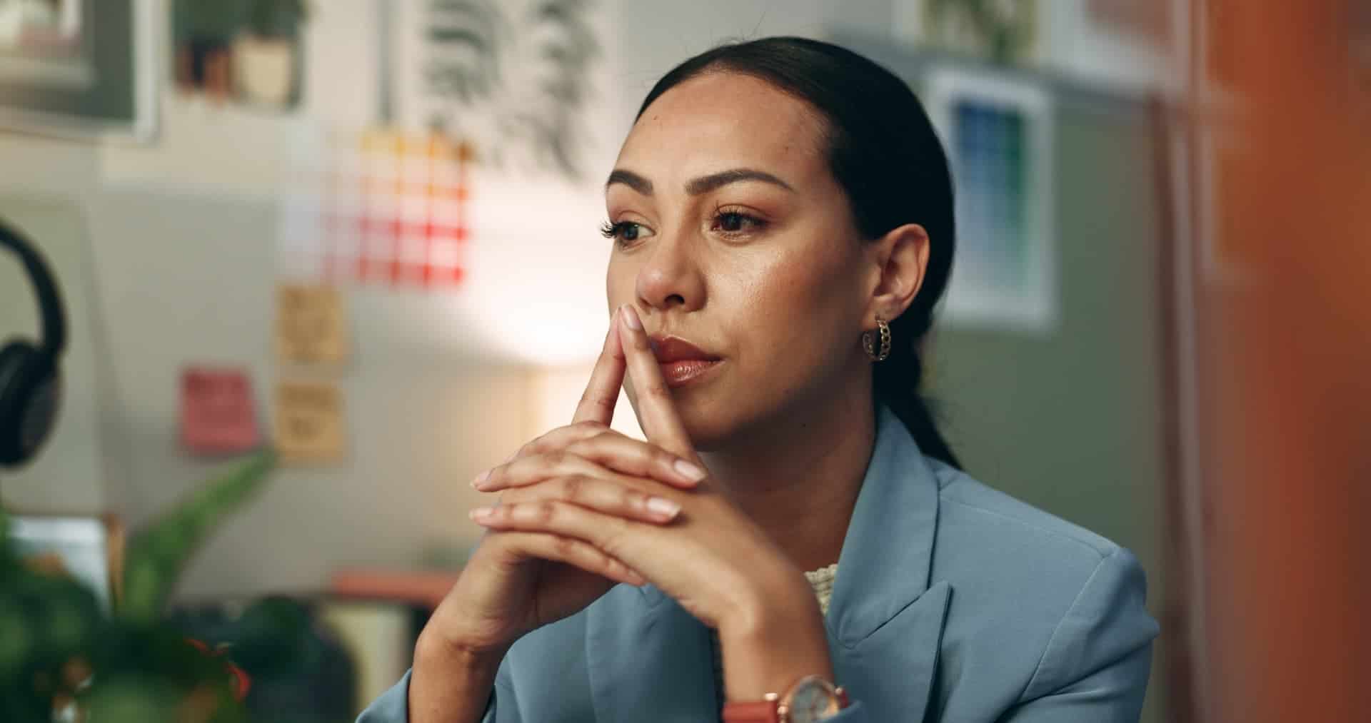 Closeup of a woman in her office thinking through a decision considering factors outside her immediate context