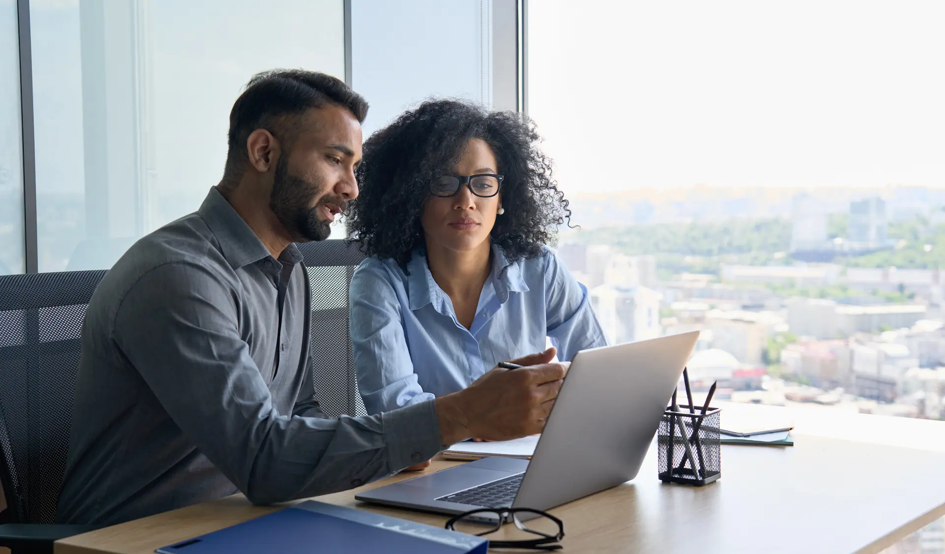 A man and woman sitting together looking over a laptop, as she gets advise from her advisor.