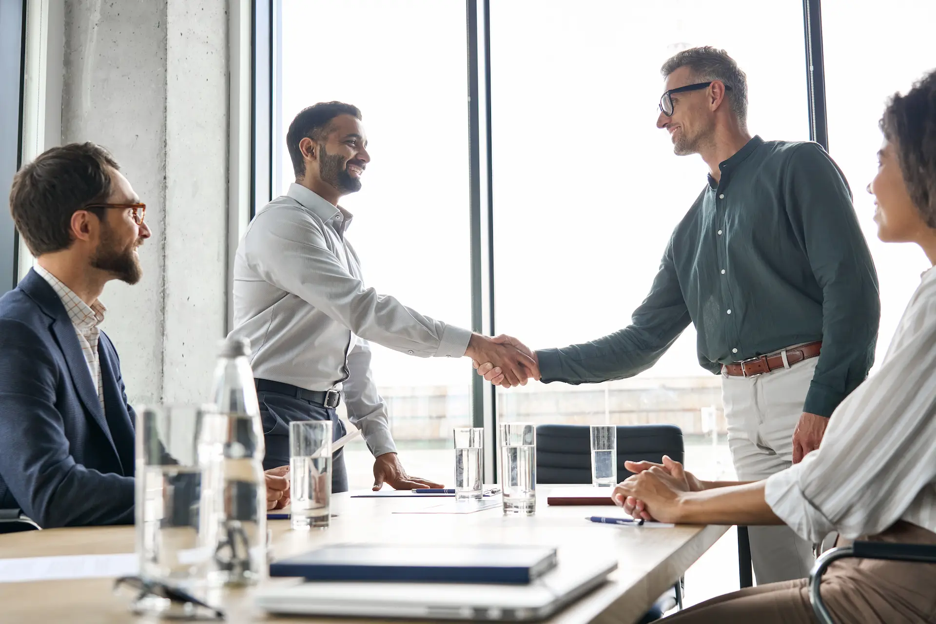 Two men shake hands in a meeting, symbolizing mutual respect and professional influence and power.