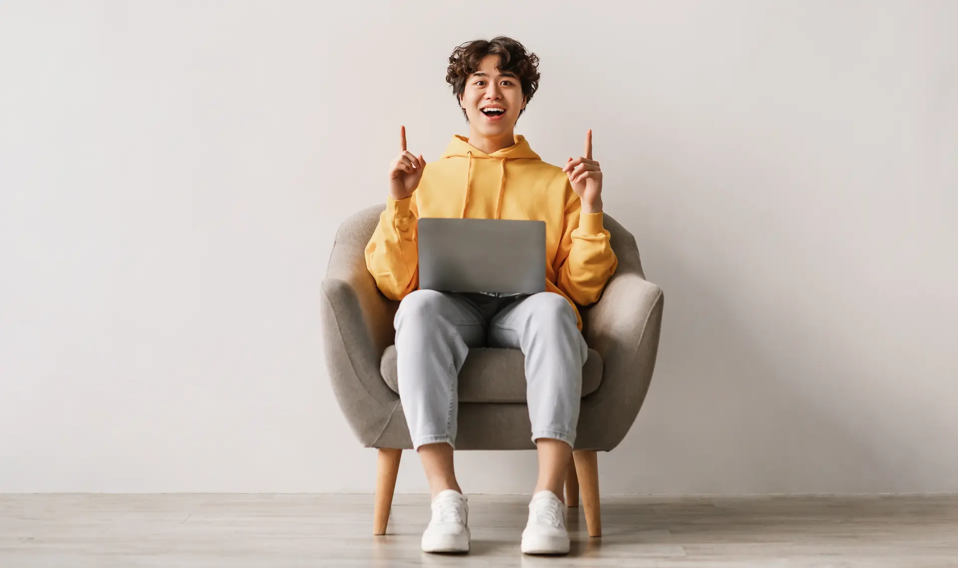 A man sits with a laptop on his legs, smiling and giving a thumbs up, suggesting he just had a creative idea through improvisation.