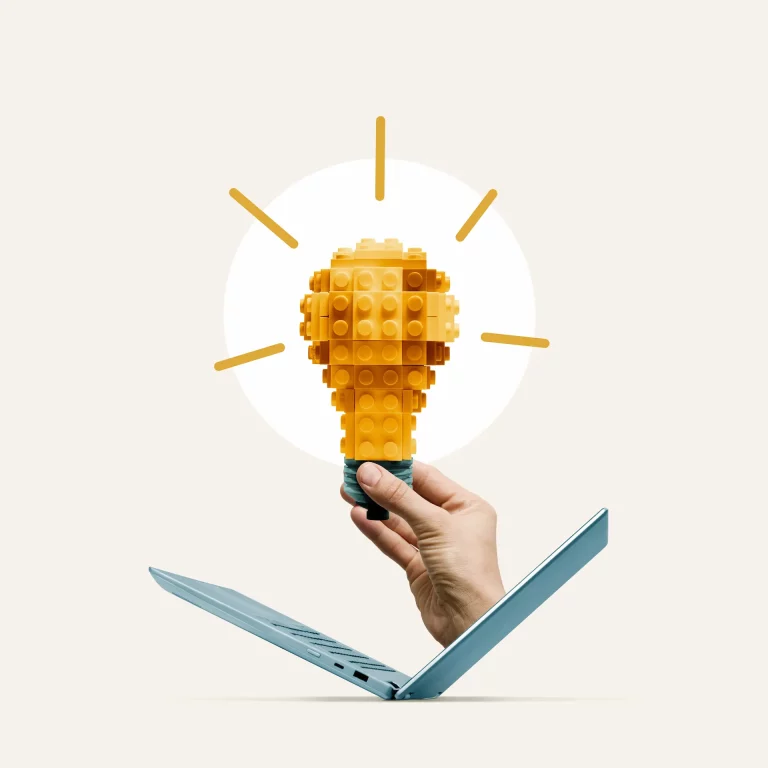 A hand emerges from a laptop holding a lightbulb, symbolizing improvisation, idea generation, and innovation.
