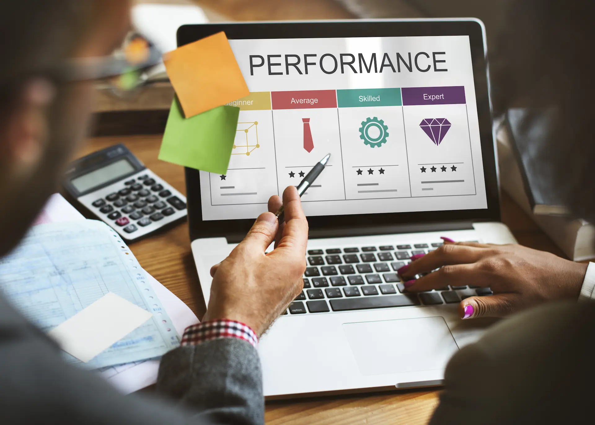 A man and woman analyze performance data on a laptop, demonstrating organizational agility through assessment and adaptation.