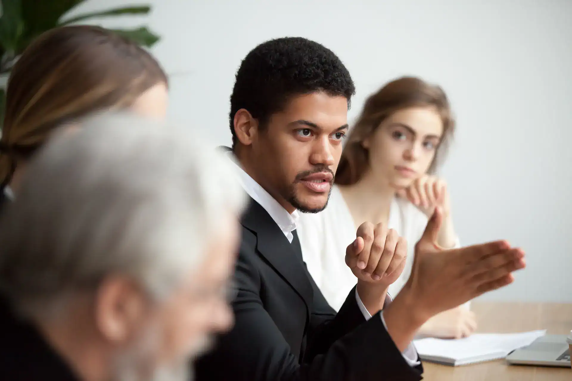 A manager gestures toward a team member in a meeting, illustrating active delegation of responsibilities.