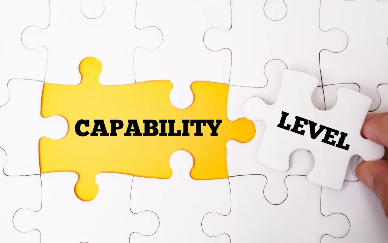 A hand lifts a puzzle piece labeled “level,” revealing the word “capability” underneath, symbolizing growth and discovery.