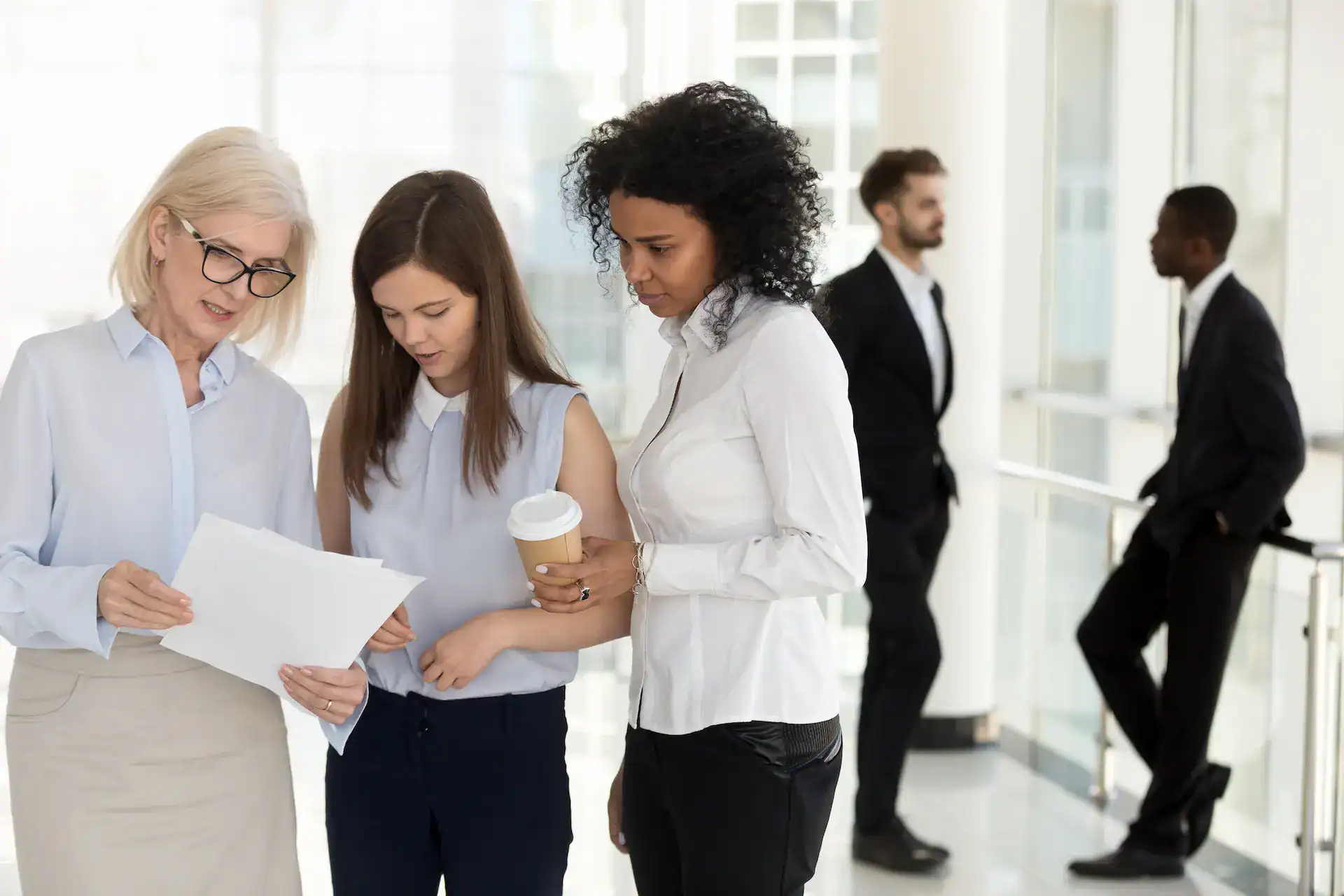 A manager reviews a document with her team, showing follow-up and feedback on delegated work.