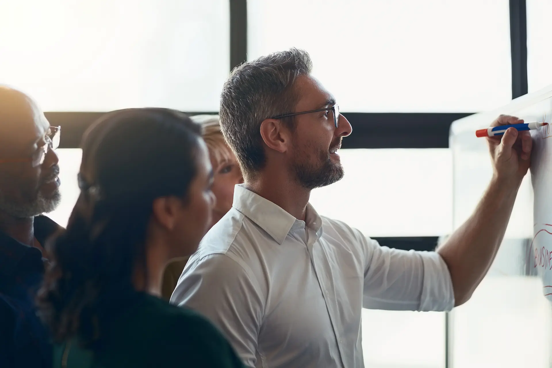 An example of followership in action, where team members attentively watch a leader explain strategy on a whiteboard.