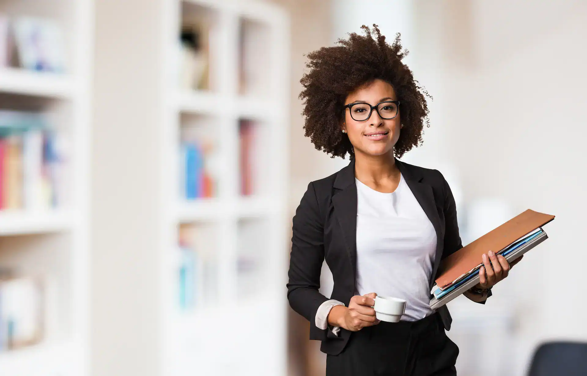 A woman in her office, confidently showing her success because of her ability to navigate her organization successfully.